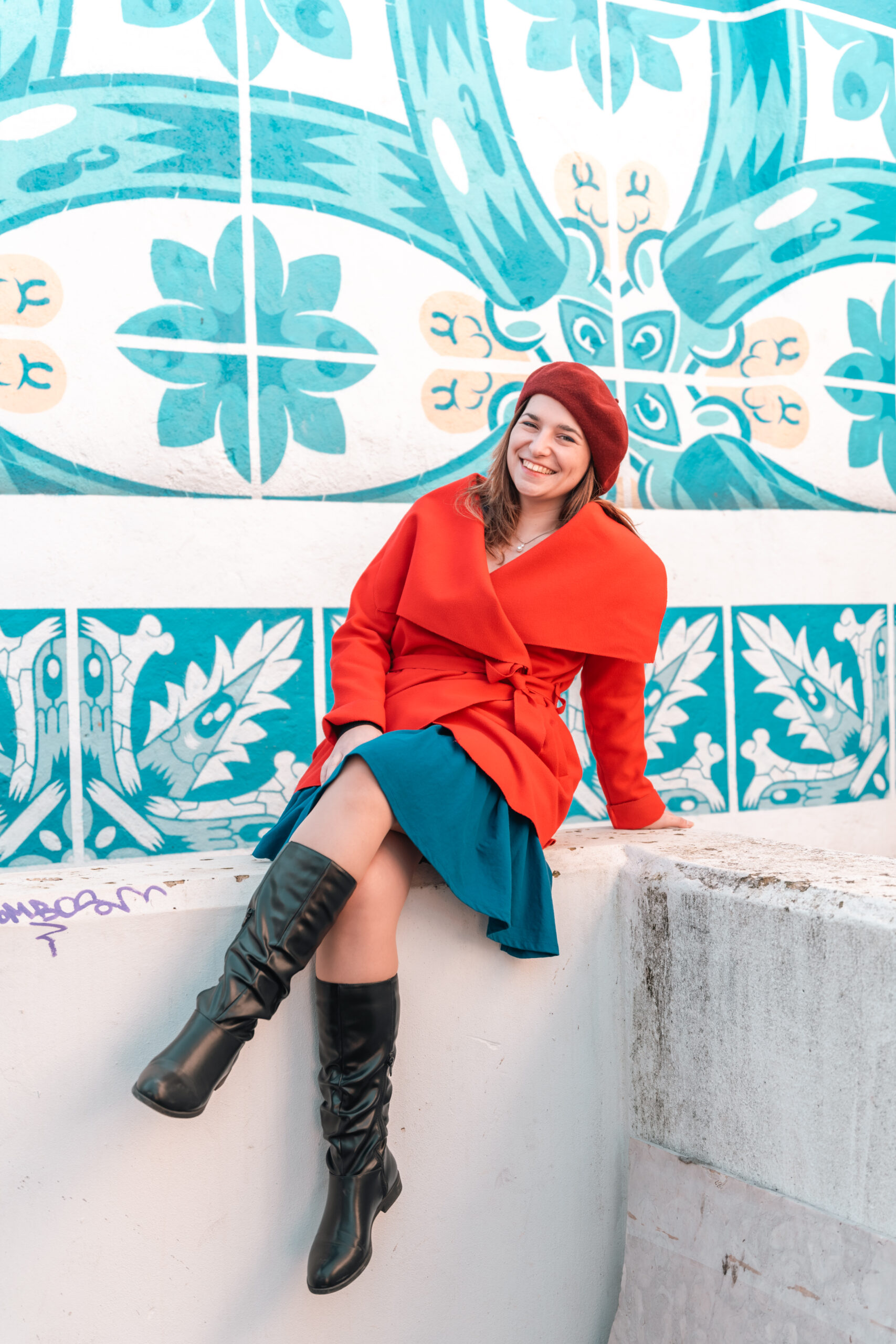 girl standing in front of a red door wearing a red coat